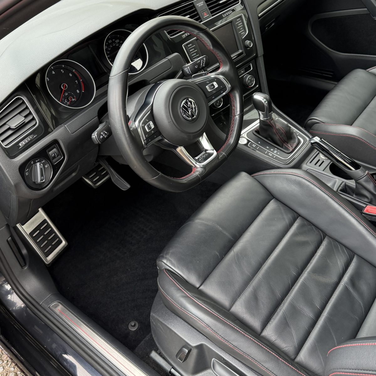The same Volkswagen GTI interior after detailing, with a clean floor and conditioned leather seats
